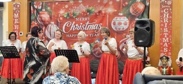 The singers performing in front of a Merry Christmas backdrop